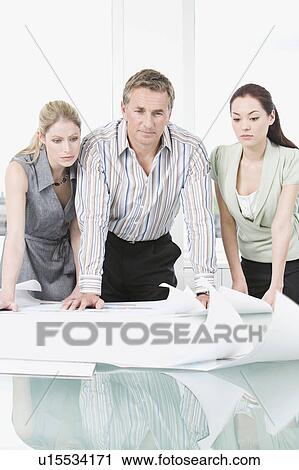 Three colleagues looking at some plans View Large Photo Image Stock Image - Three colleagues looking at some plans. Fotosearch