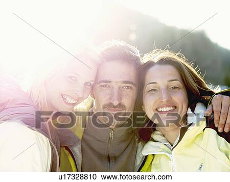 Stock Image - three friends in snow on hillside. Fotosearch