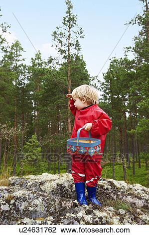 Stock Image - Toddler standing on rock in forest. Fotosearch
