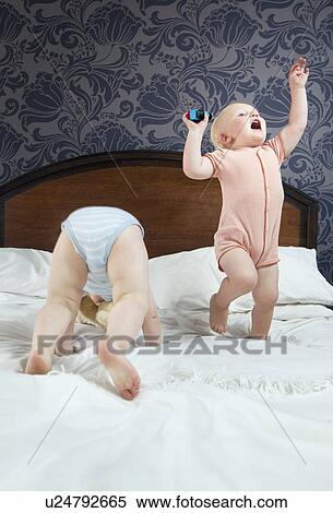 Two baby boys play on a bed View Large Photo Image Stock Photography - Two baby boys play on a bed. Fotosearch