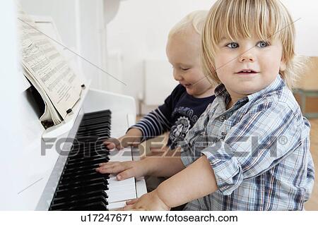Stock Image - Two boy toddlers sitting at a piano. Fotosearch