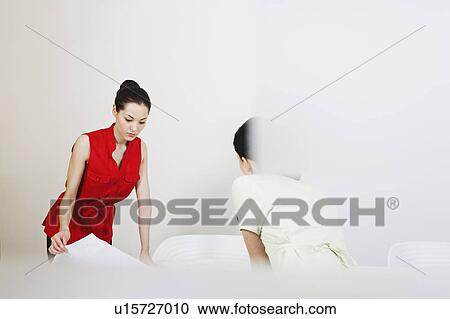 Stock Image - Two business woman looking at plans. Fotosearch