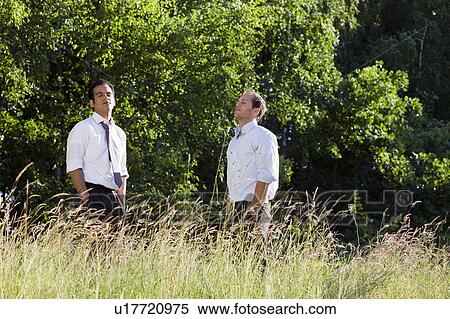Stock Photography - two businessmen standing in field. Fotosearch