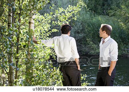 Picture - two businessmen talking on lakefront. Fotosearch