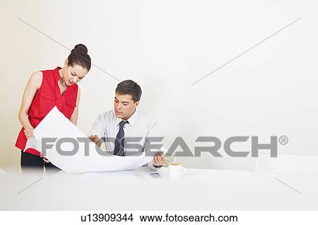 Two colleagues conferring over plans View Large Photo Image Picture - Two colleagues conferring over plans. Fotosearch