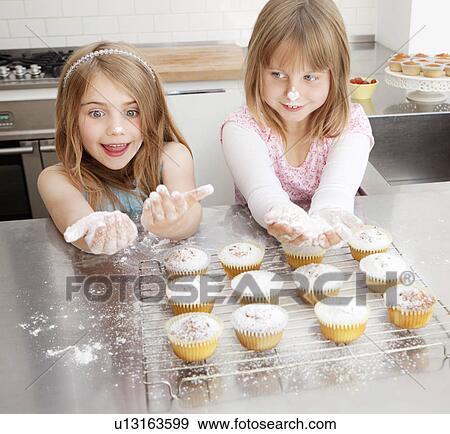 Two girls baking with icing sugar View Large Photo Image Stock Photo - Two girls baking with icing sugar. Fotosearch