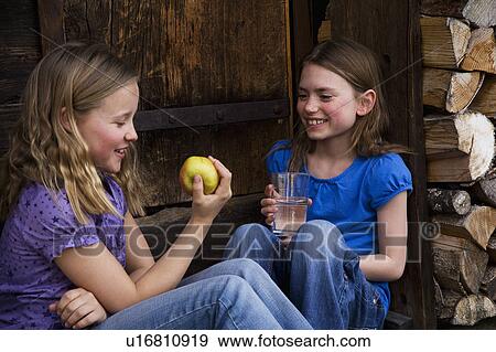 Stock Photo - Two girls eating fruit & drinking water.. Fotosearch