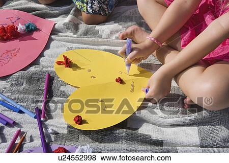 Stock Photo - Two girls making paper hearts. Fotosearch