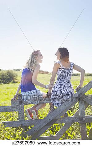 two girls sitting on a fence View Large Photo Image Stock Photo - two girls sitting on a fence. Fotosearch
