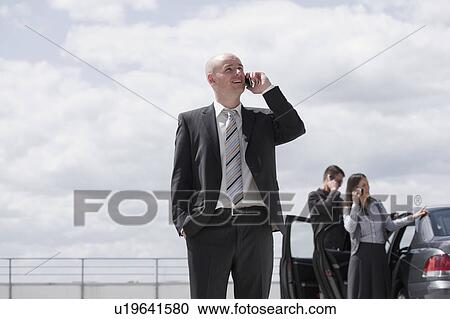 Stock Image - two men and a woman with phones. Fotosearch