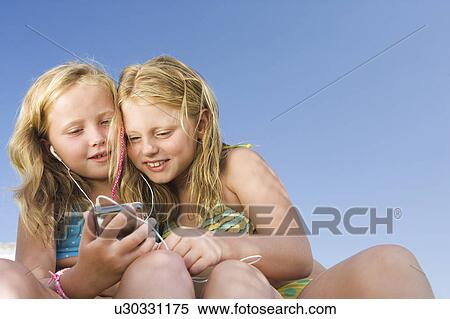 Two young girls sharing an ipod View Large Photo Image Stock Photography - Two young girls sharing an ipod. Fotosearch
