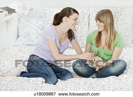Stock Photo - Two young woman with pet rabbit. Fotosearch