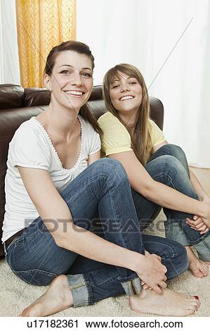 Two young women sitting on the floor View Large Photo Image Stock Image - Two young women sitting on the floor. Fotosearch