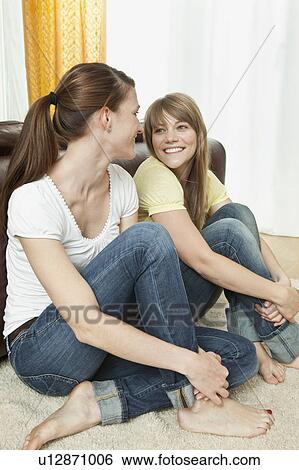 Two young women sitting on the floor View Large Photo Image Stock Photograph - Two young women sitting on the floor. Fotosearch