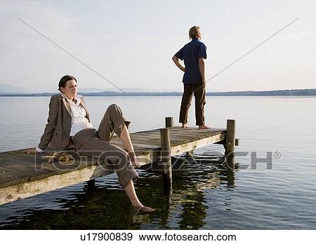 Stock Photo - woman and man on pier at lake. Fotosearch