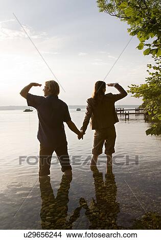Picture - woman and man standing in lake. Fotosearch