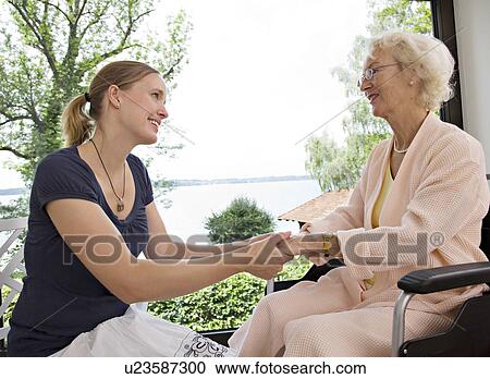 Stock Image - woman and senior woman holding hands. Fotosearch