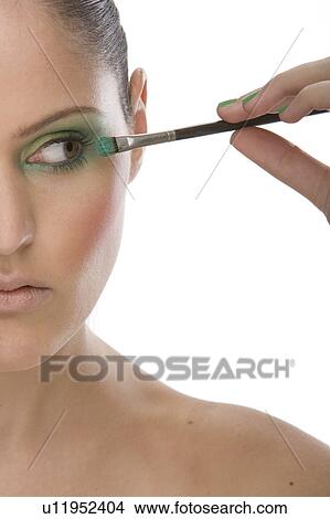 Picture - Woman applying eye makeup up with brush. Fotosearch