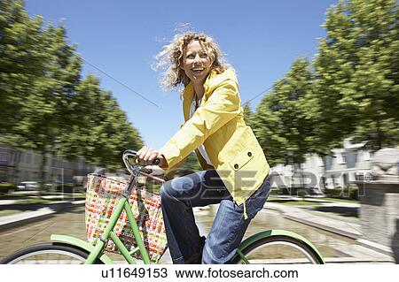 Woman bicycling across the city View Large Photo Image Stock Image - Woman bicycling across the city. Fotosearch