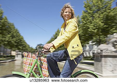 Woman bicycling with shopping bag View Large Photo Image Stock Image - Woman bicycling with shopping bag. Fotosearch