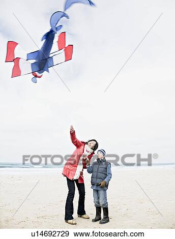 Stock Photo - Woman & boy on beach with kite. Fotosearch
