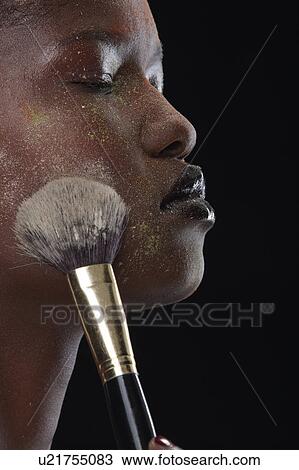 Woman brushing makeup on her face View Large Photo Image Stock Image - Woman brushing makeup on her face. Fotosearch