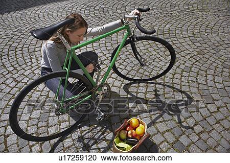Stock Image - Woman checking up her bike. Fotosearch