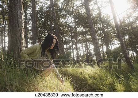 Stock Photo - Woman crouching engaging in nature. Fotosearch