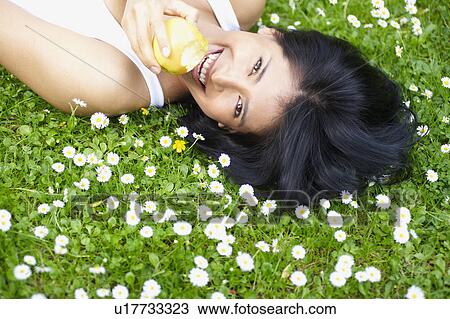 Woman eating an apple in the daisies View Large Photo Image Stock Image - Woman eating an apple in the daisies. Fotosearch