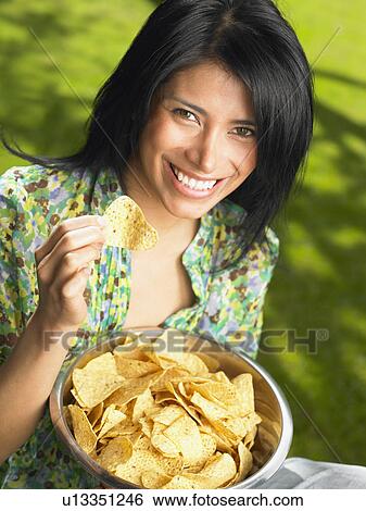 Stock Photograph - Woman eating chips, outdoors. Fotosearch