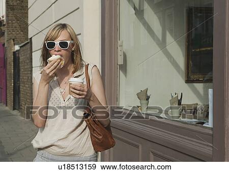 Stock Photo - Woman eating in street. Fotosearch
