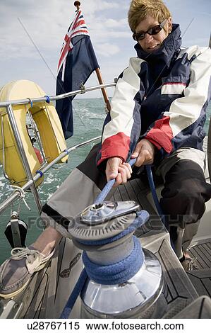 Stock Photography - Woman hoisting sails on yacht. Fotosearch