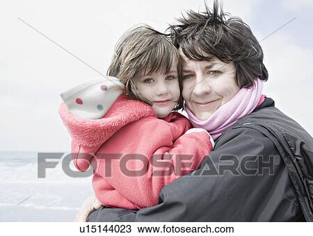 Stock Image - Woman holding child on beach. Fotosearch