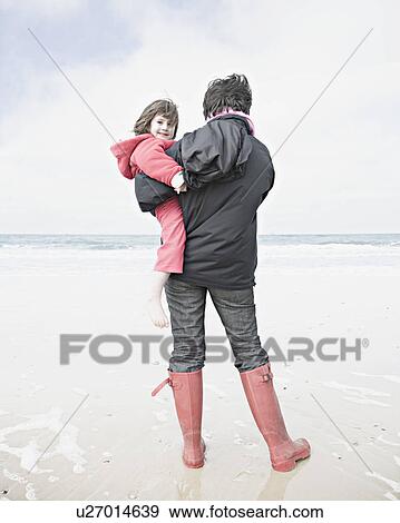 Woman holding child on beach View Large Photo Image Stock Photo - Woman holding child on beach. Fotosearch
