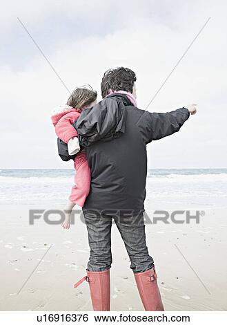Stock Photograph - Woman holding child on beach. Fotosearch