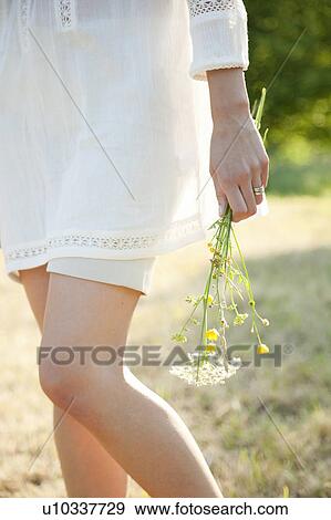 Stock Photo - Woman holding flowers in countryside. Fotosearch