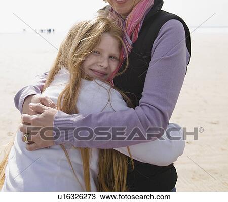 Woman hugging girl on beach View Large Photo Image Stock Image - Woman hugging girl on beach. Fotosearch