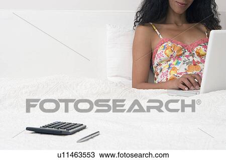 Stock Image - woman in bed with a computer. Fotosearch