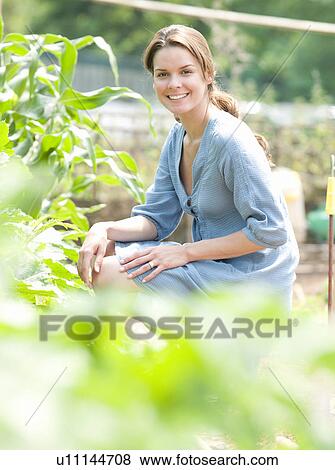Woman kneeling around plants in country View Large Photo Image Stock Photo - Woman kneeling around plants in country. Fotosearch