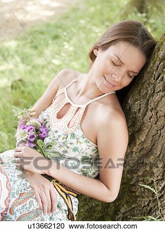 Stock Image - woman lying against tree. Fotosearch