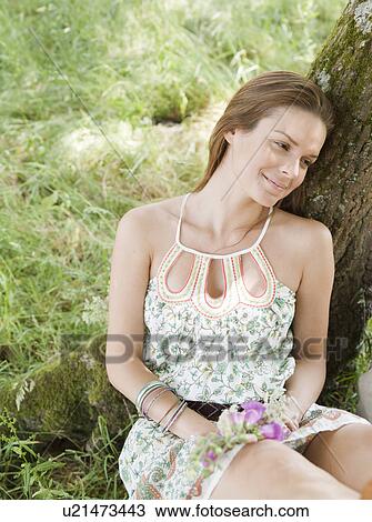 Stock Image - woman lying against tree. Fotosearch