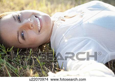 Picture - Woman lying in grass in country. Fotosearch