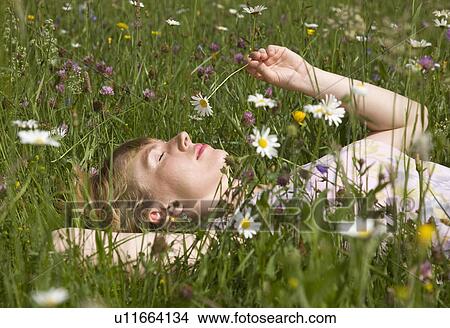 Picture - woman lying in grass with spring flowers. Fotosearch