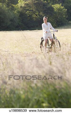 Stock Photo - Woman on bicycle in countryside. Fotosearch