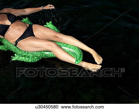 Stock Image - Woman on inflatable crocodile. Fotosearch