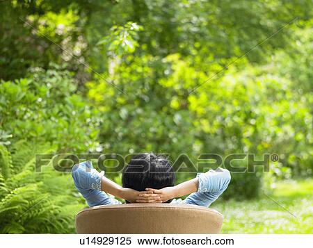 Stock Photography - Woman on sofa, in the garden. Fotosearch