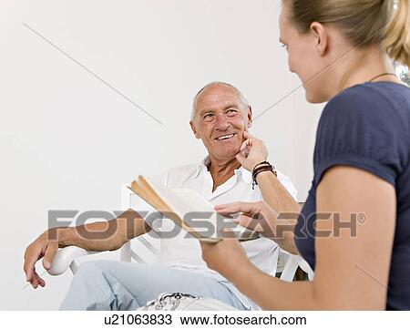 Stock Image - woman reading book to senior man. Fotosearch