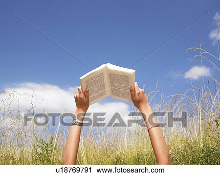 Stock Image - woman reading in field of high grasses. Fotosearch