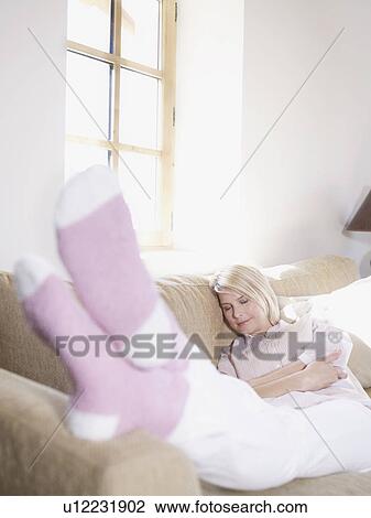 Stock Image - woman relaxing, feet up in living room. Fotosearch