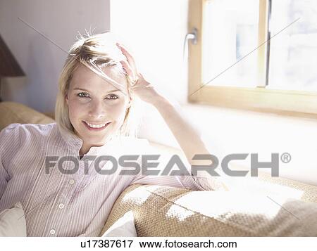 Stock Photo - woman relaxing on sofa in living room. Fotosearch